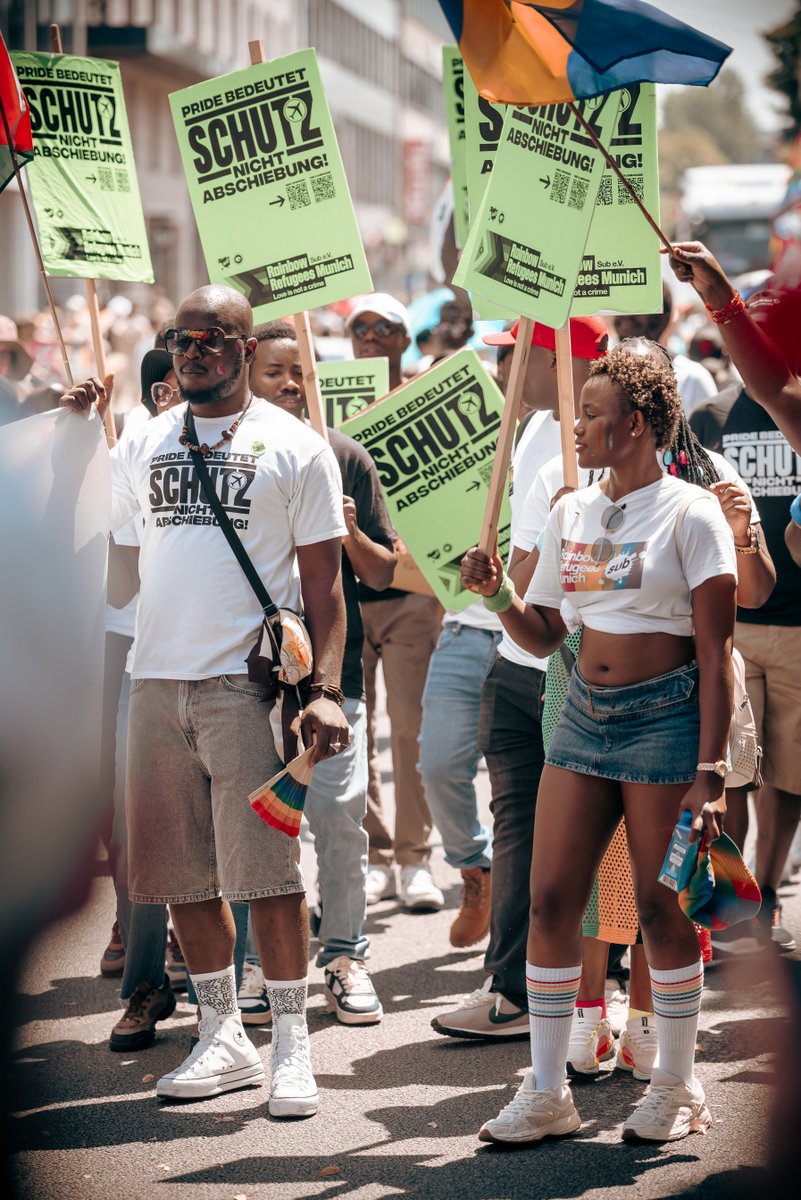 Gruppe von Rainbow Refugees Munich demonstriert beim CSD mit Schildern gegen Abschiebungen und für den Schutz queerer Geflüchteter.