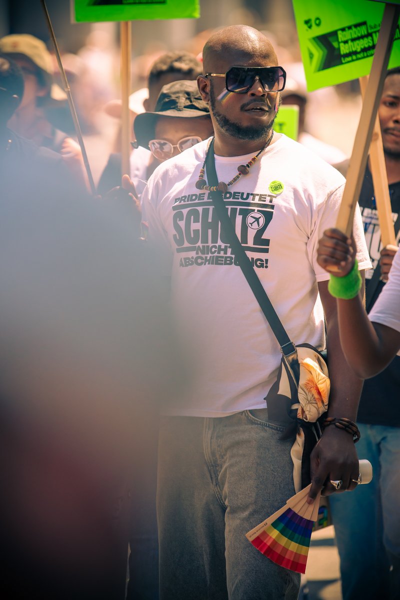 Teilnehmer mit Pride-T-Shirt und Regenbogenf?her demonstriert gemeinsam mit Rainbow Refugees Munich f? Menschenrechte.