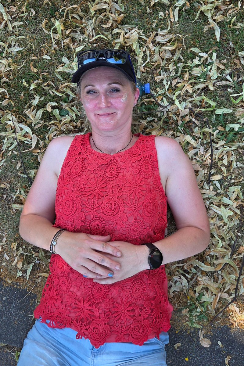 Besucherin in rotem Oberteil sitzt im Schatten und macht eine kurze Pause von der Pride-Parade.