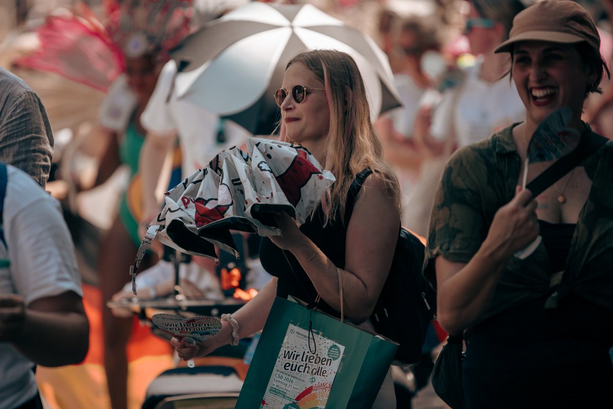 Gruppe von Teilnehmenden und Motorr?ern mit Pride-Schmuck inmitten der Parade.