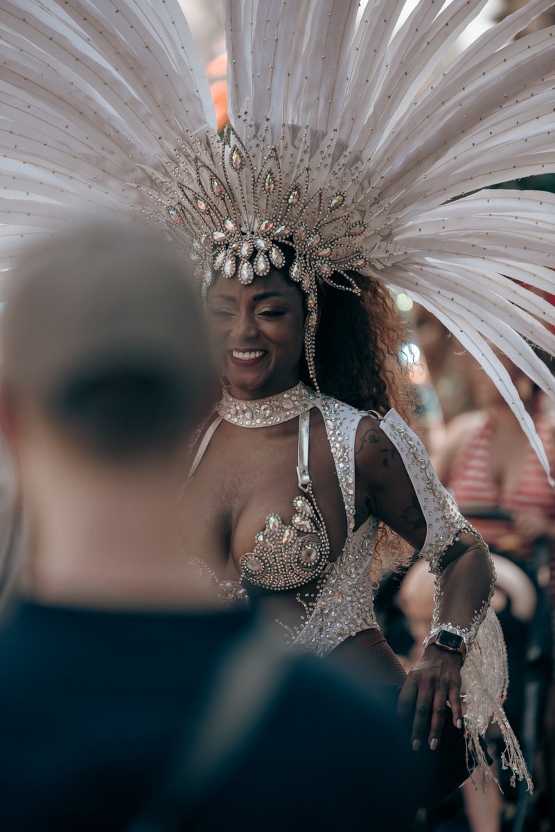 Drag Artist mit gro?m wei?m Federkopfschmuck und schimmerndem Outfit steht im Mittelpunkt der Parade.