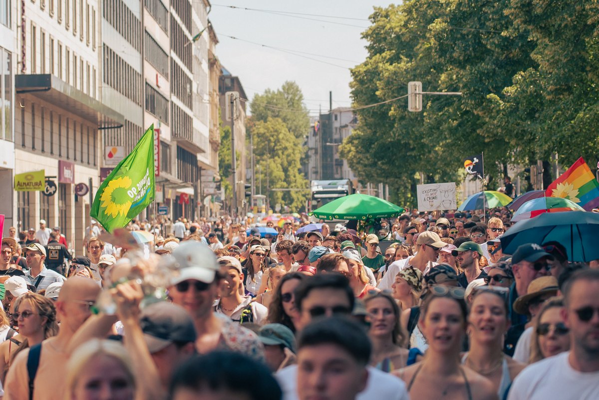 Menschenmenge beim CSD mit vielen H?en, Fahnen und gr?en Pride-Schildern.