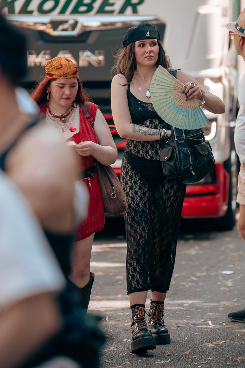 Teilnehmerin in schwarzem Outfit und Hut l?ft mit F?her durch die Parade.
