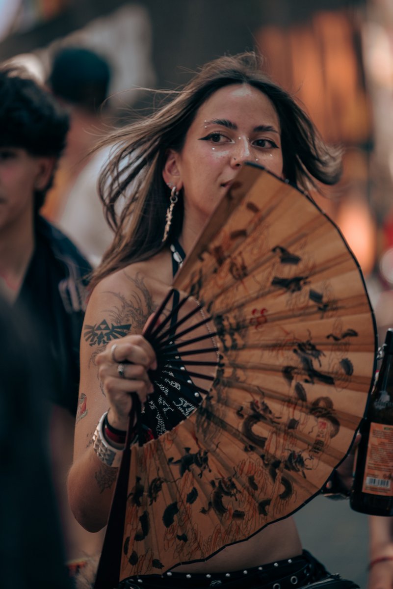 Besucherin mit F?her und sommerlichem Outfit schaut aufmerksam zur Parade.