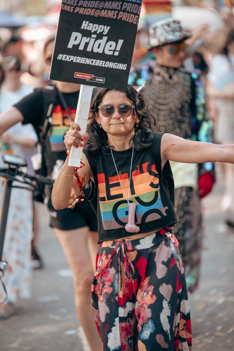Teilnehmerin mit Schild und Regenbogenf?her demonstriert f? queere Sichtbarkeit und Pride.