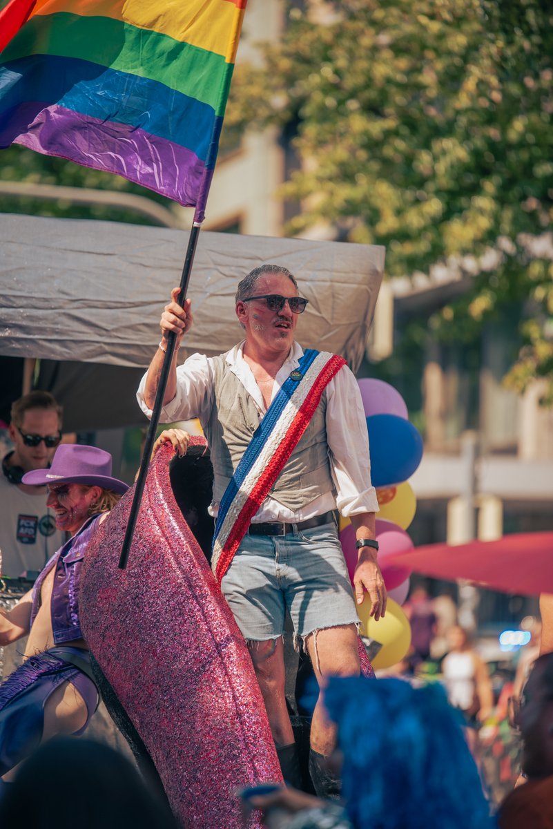 Person reitet auf einem rosafarbenen Einhorn-Kost? und tr?t eine Regenbogensch?pe.
