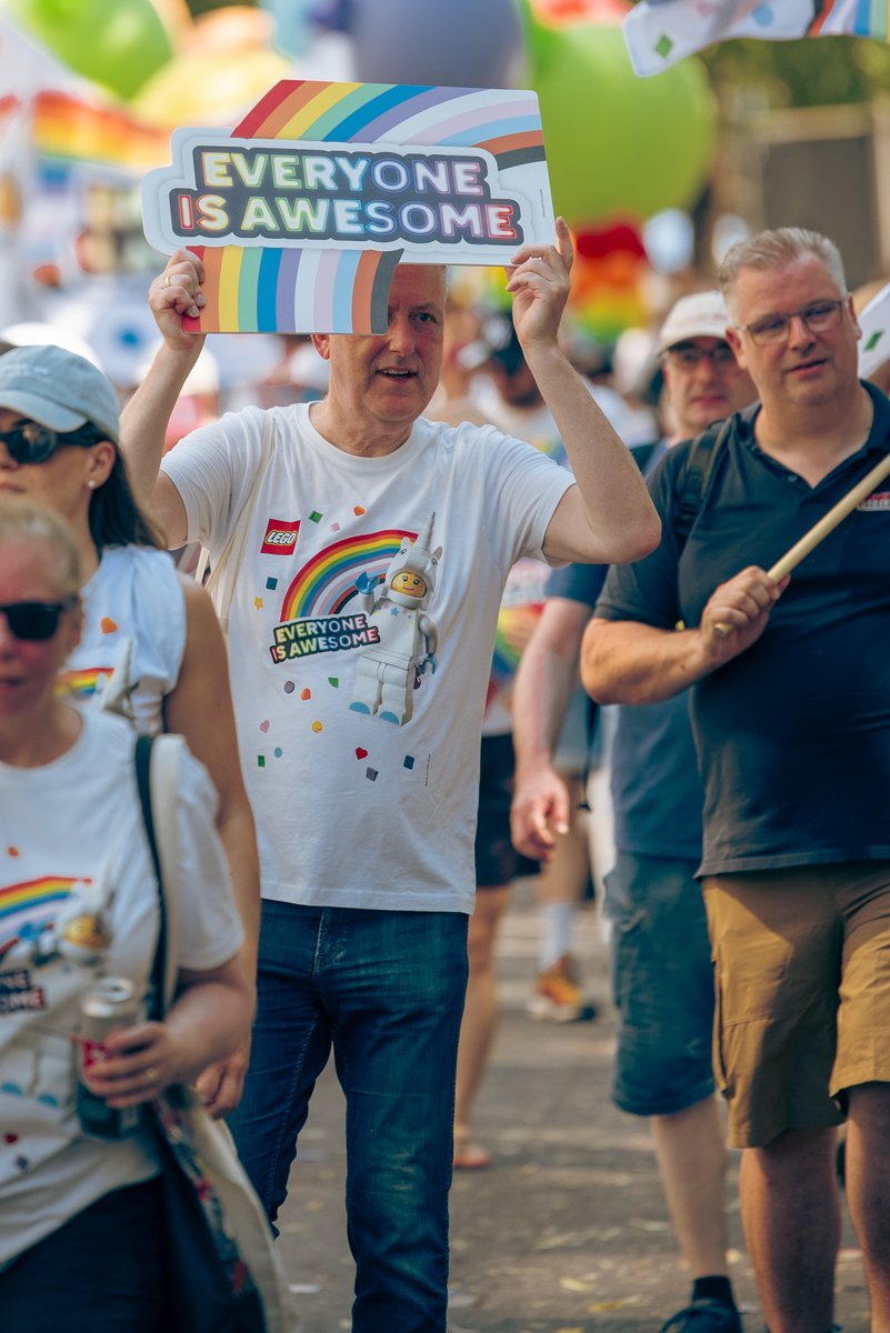 Personen mit ?Everyone is awesome?-Schildern laufen unter bunten Ballons durch die Parade.