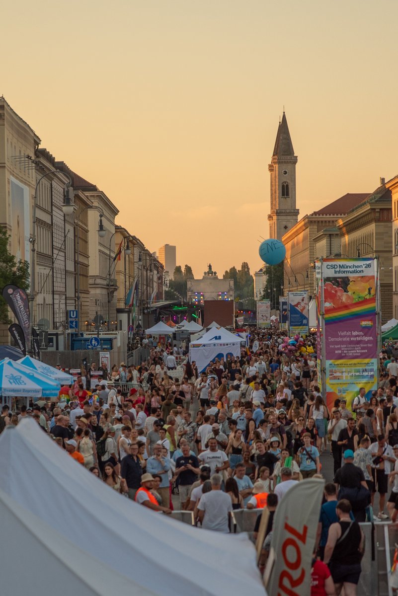 Menschenmenge f?lt bei Sonnenuntergang die Stra? vor Pride-St?den und Festzelten.