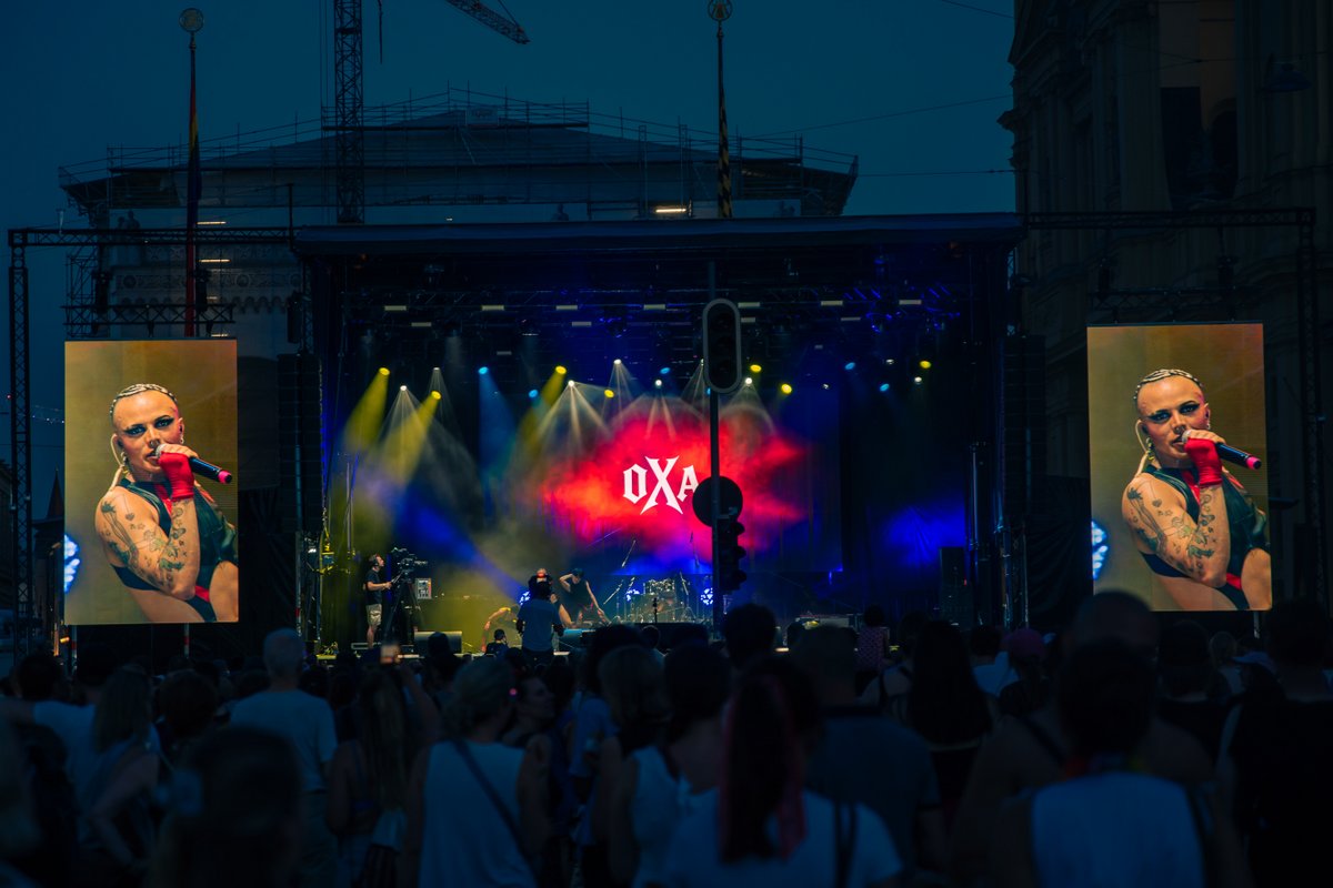 B?ne mit buntem Licht und Projektion, davor tanzt die Menge bei der Pride-Party.