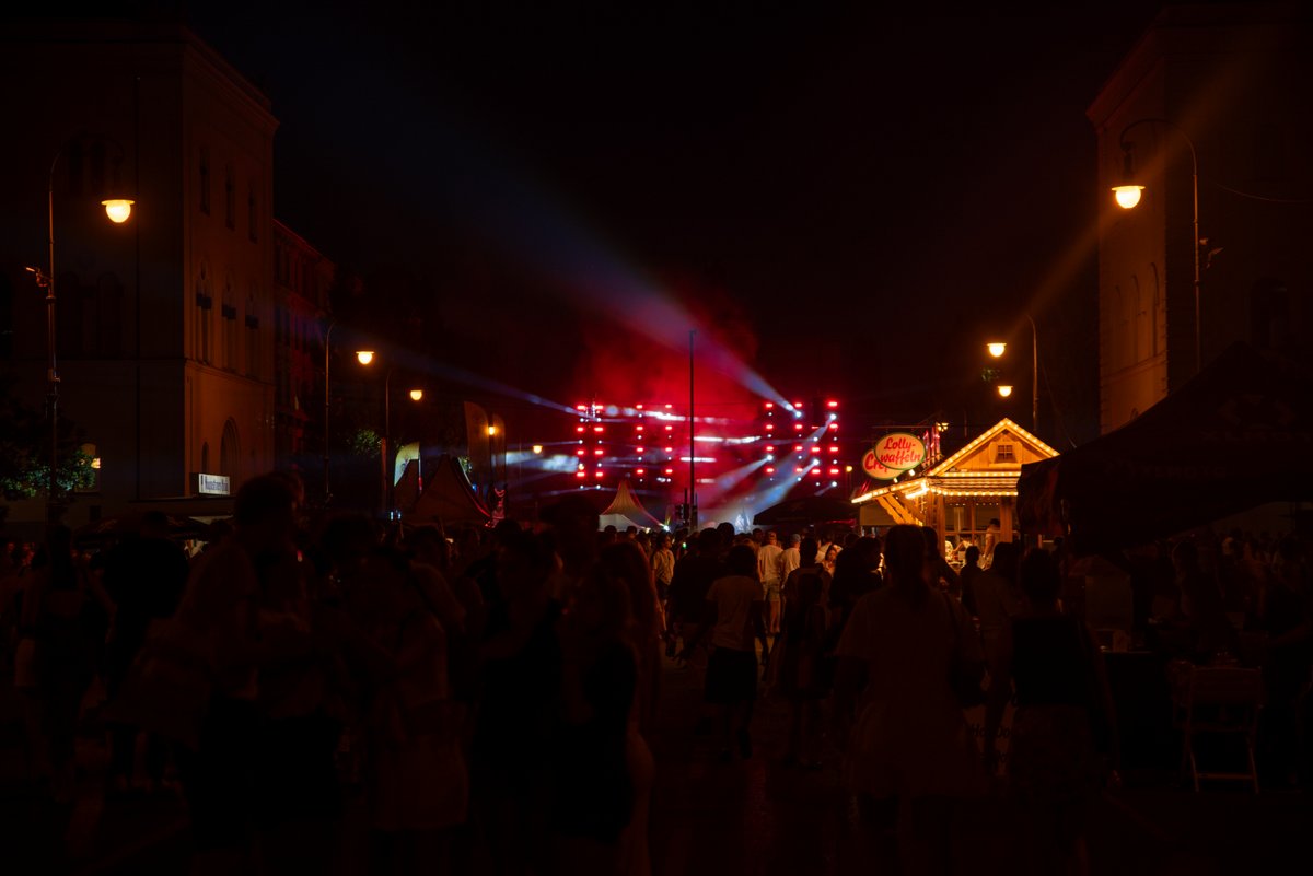 Dunkle Stra? mit rotem B?nenlicht und vielen Menschen bei der Pride-Party am Abend.